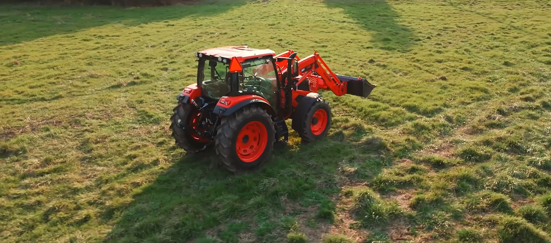 Red tractor with front loader working in a grass field